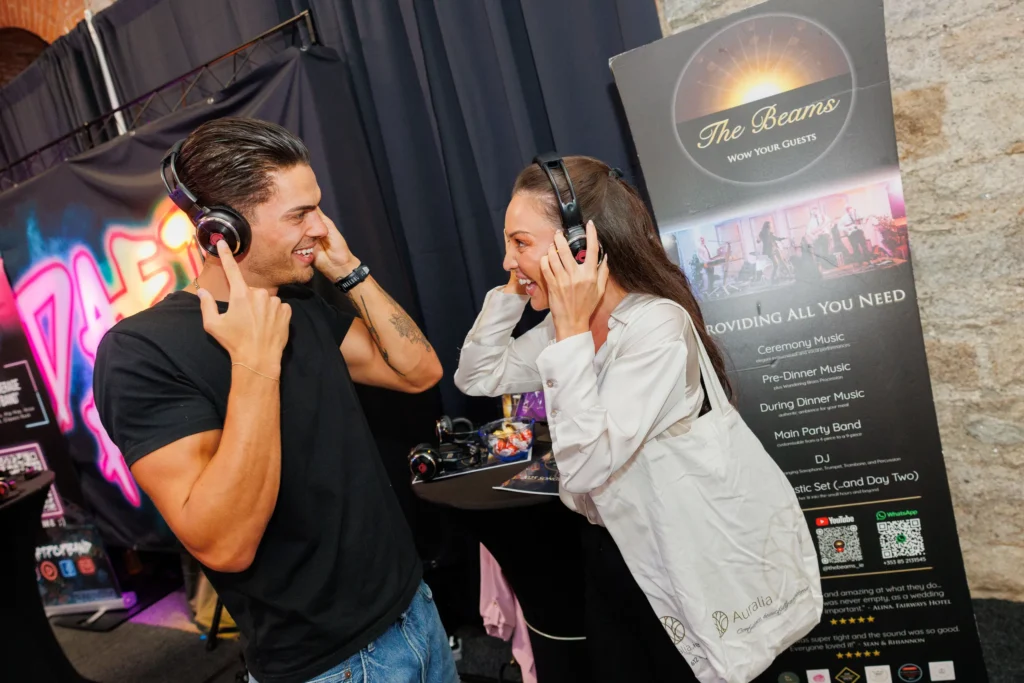 Couple enjoying music with headphones at a vibrant exhibition booth.
