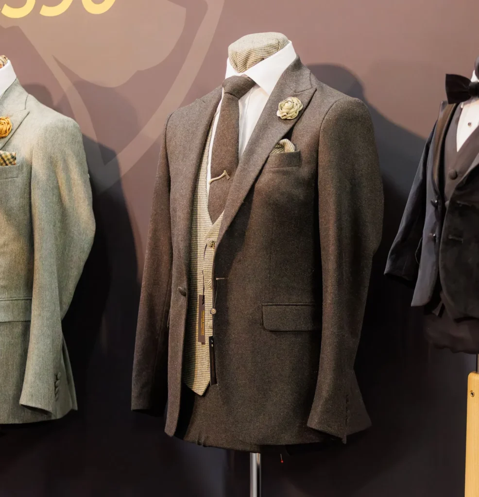 Elegant brown suit display with tie and pocket square on mannequin at men's fashion showcase.