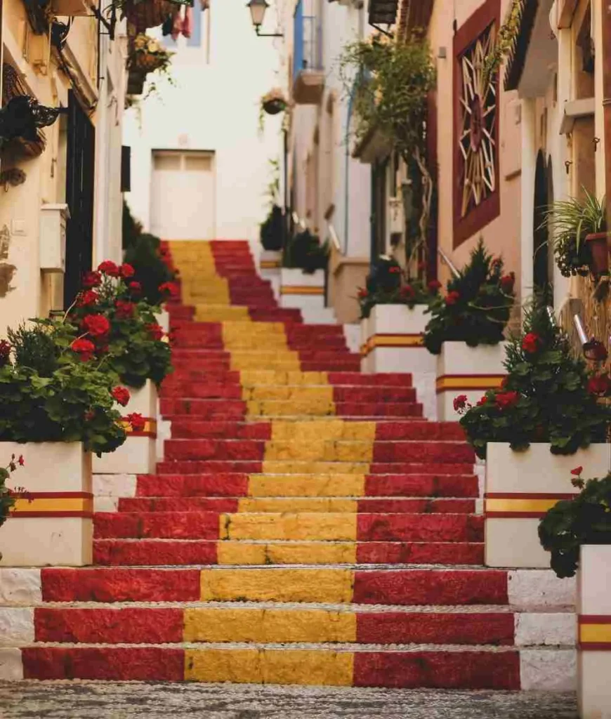 Colorful city stairs adorned with vibrant red and yellow stripes, surrounded by lush potted plants and flowers.