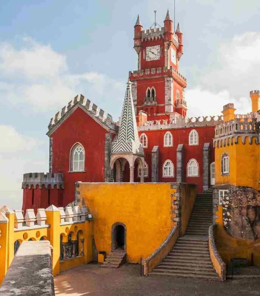 Vibrant exterior of Pena Palace in Sintra, Portugal, showcasing red and yellow walls with intricate architectural details.