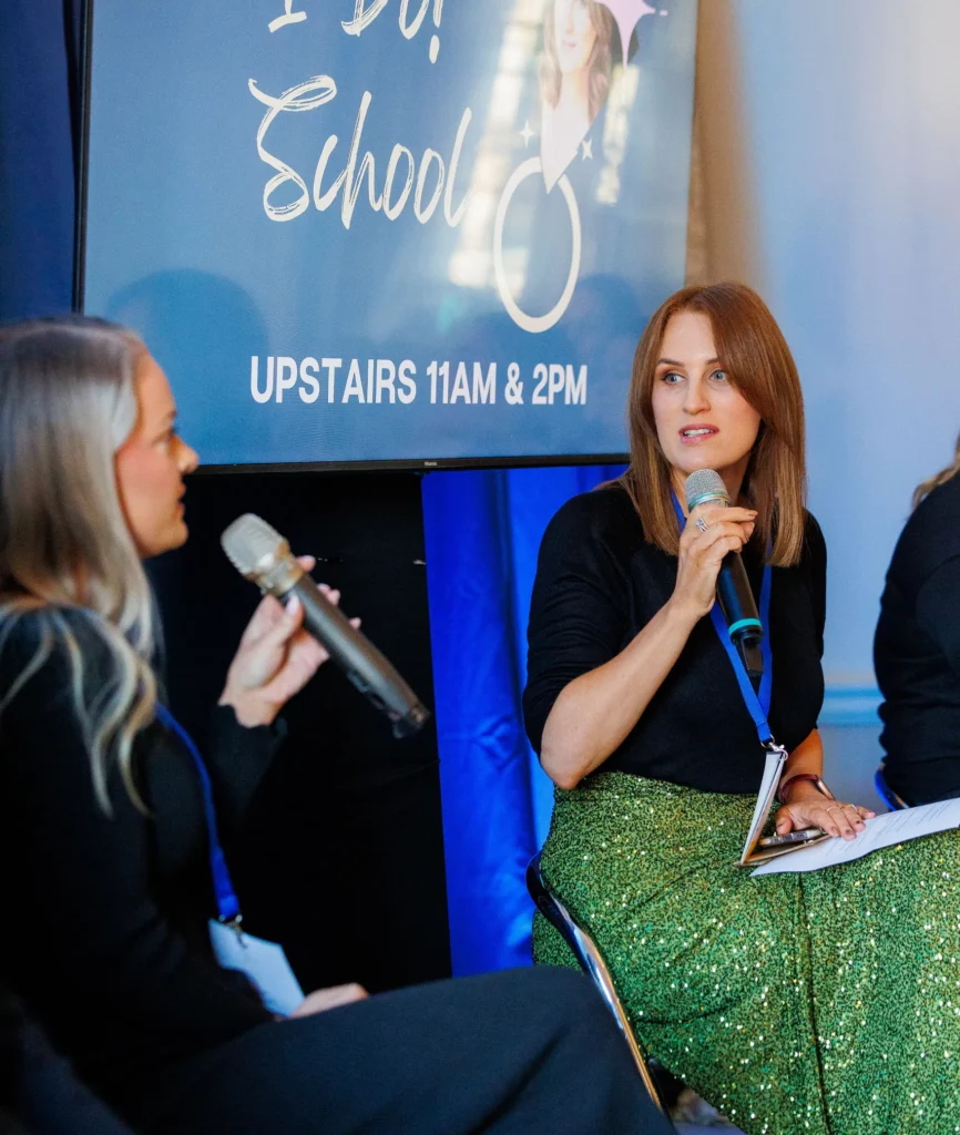 Women speaking at an event, discussing topics at I Do School with microphones on stage.