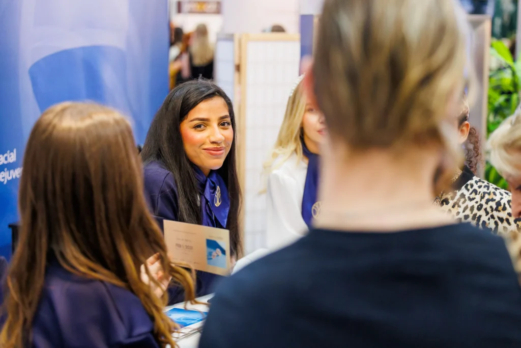 Smiling representative engages customers at a vibrant business expo booth.