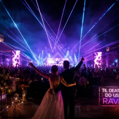Couple at vibrant rave wedding celebration with lasers, neon lights, and a lively crowd.