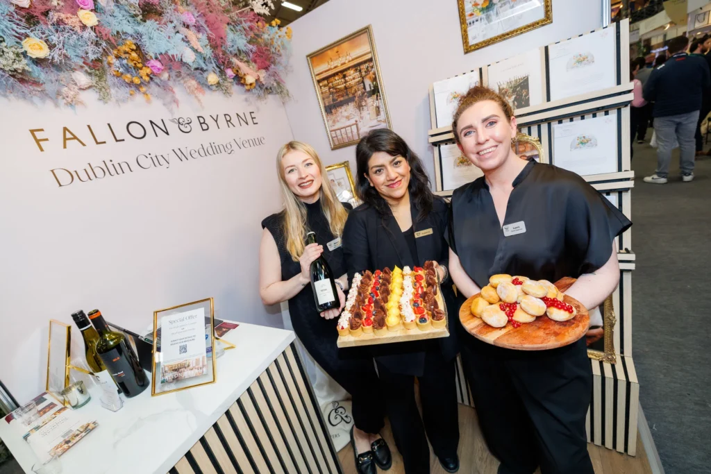 Three staff members showcase desserts and wine at Fallon & Byrne Dublin City Wedding Venue booth.