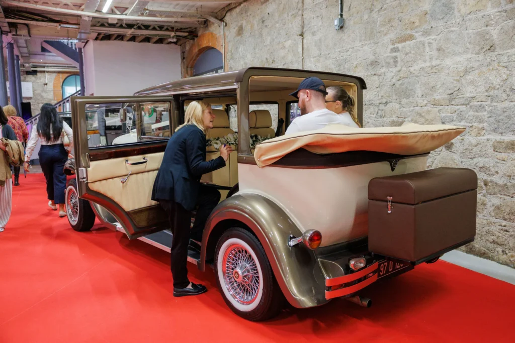 Vintage car interior showcase with people discussing at an auto exhibition on a red carpet.
