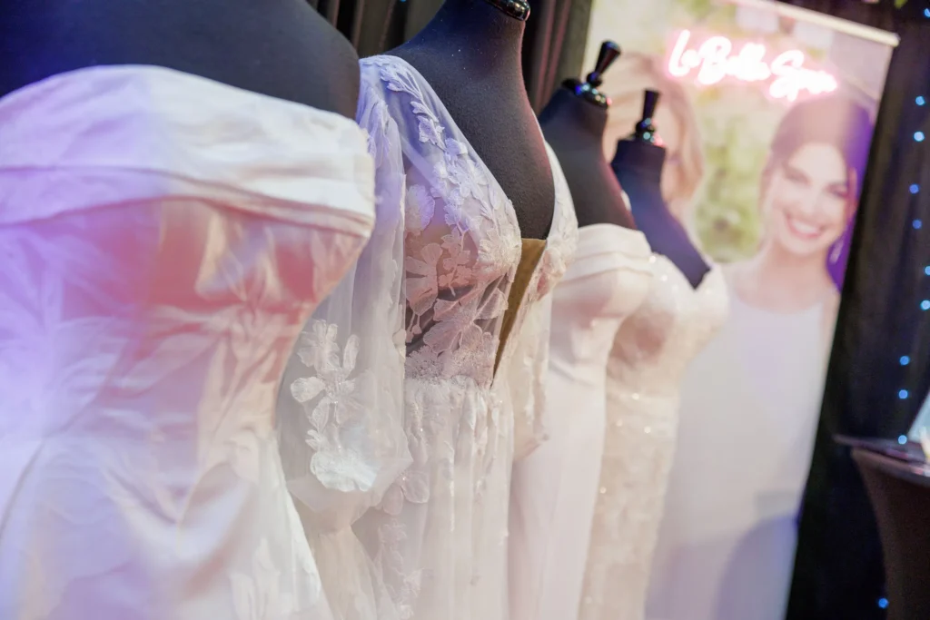 Row of elegant white wedding dresses on display mannequins at a bridal boutique showcase.