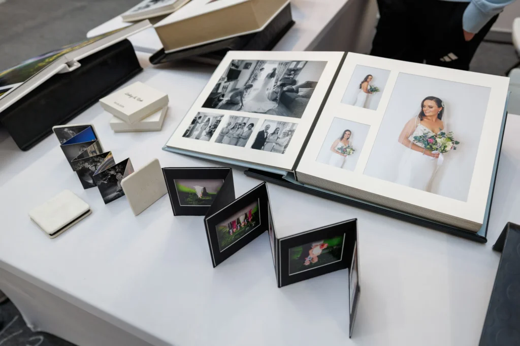 Wedding photo album display with bride portraits and black-and-white images on a table, featuring elegant packaging.