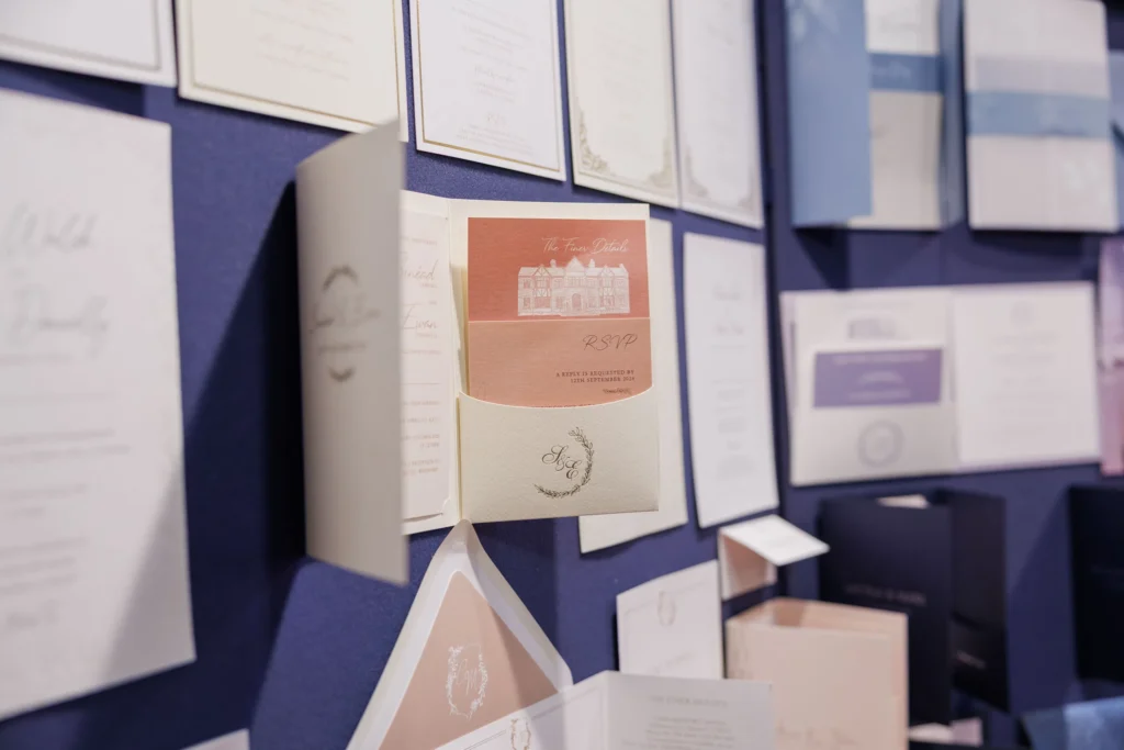 Elegant wedding invitations displayed on a blue backdrop, featuring RSVP cards and envelopes.