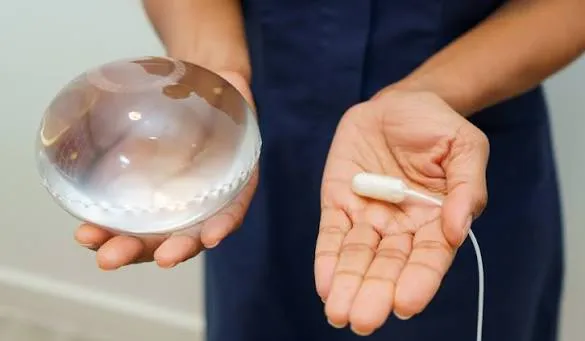 Person holding an intragastric balloon for weight loss in one hand and its capsule form in the other.