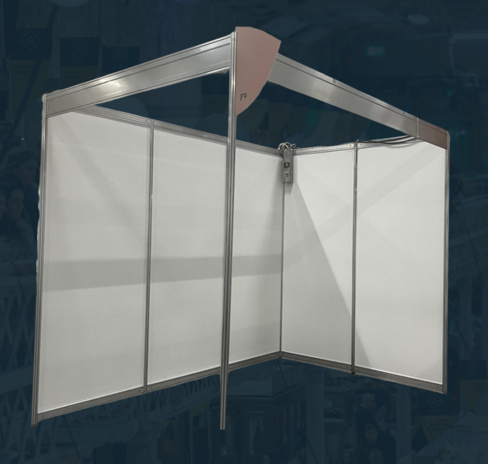 Empty exhibition booth with partition panels and metal frame, ready for setup at a trade show.