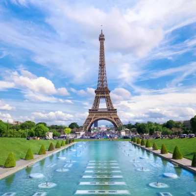 Eiffel Tower in Paris with fountain and green lawns under a bright blue sky.